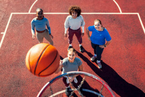Portait of diverse group of young woman having fun playing basketball outdoors.